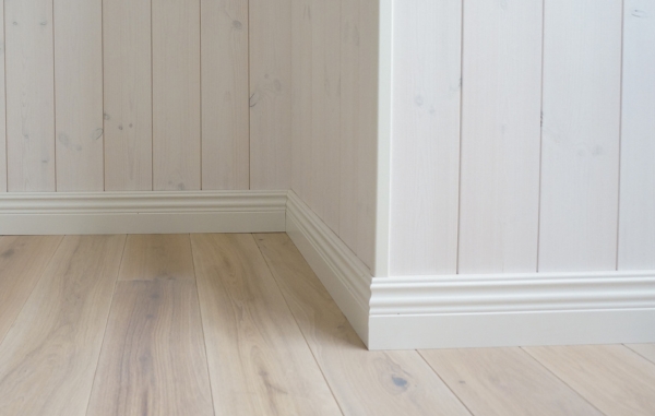 Vit golvlist och vit panel, samt trägolv