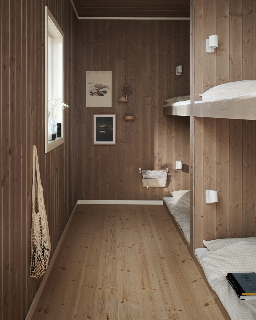 Ett rum med trä från tak till golv och vita lister, samt inbyggda våningssängar