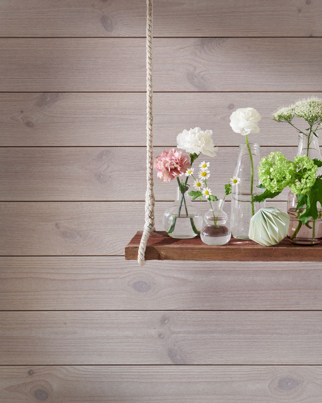 Grå liggande träpanel och en hängade hylla med blomvaser