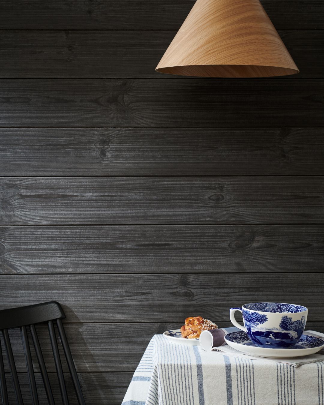 Svart liggande träpanelen Sjöbod Lava på väggen och ett dukat frukostbord