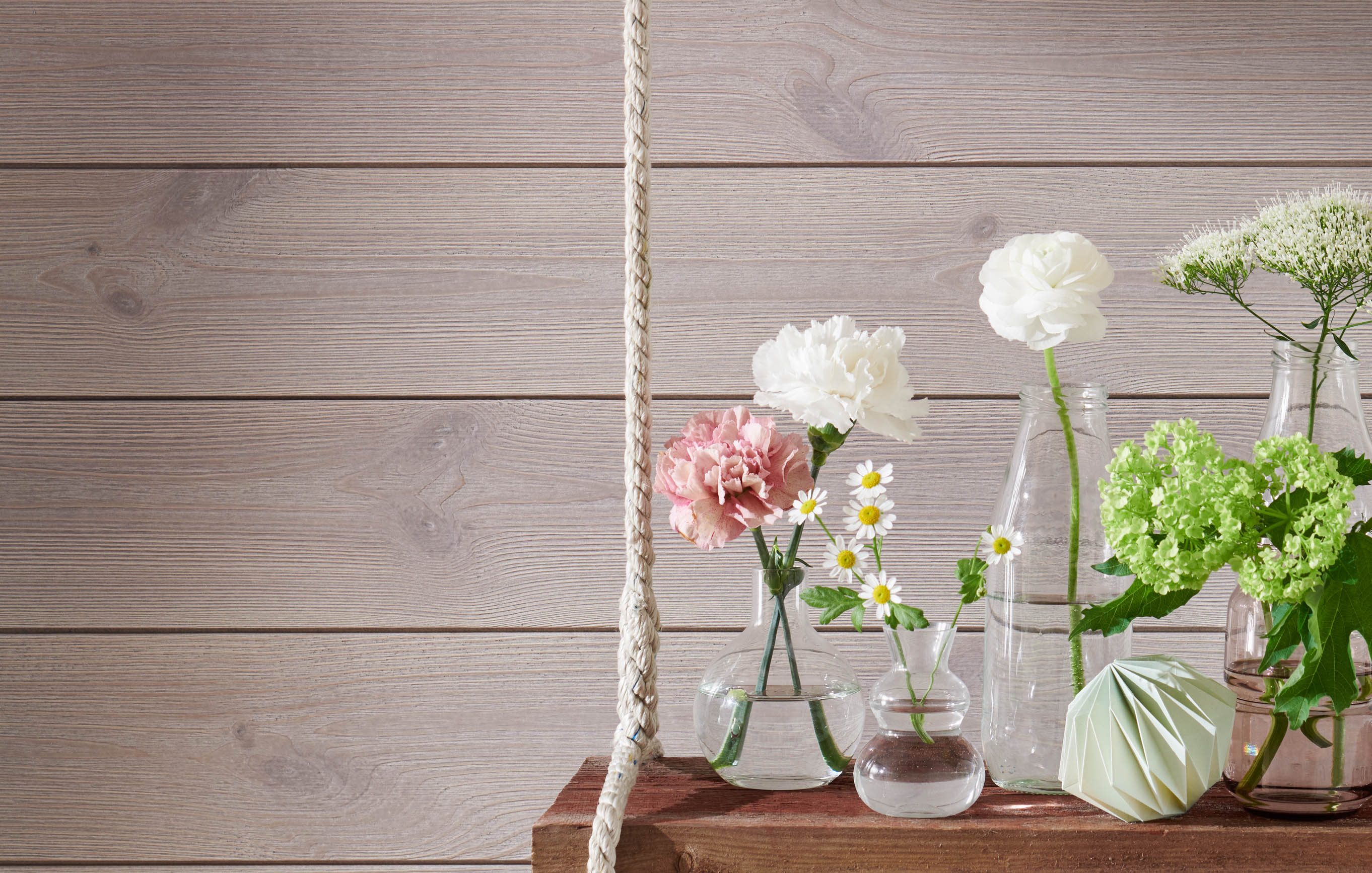 Grå träpanel på vägg och blommor framför