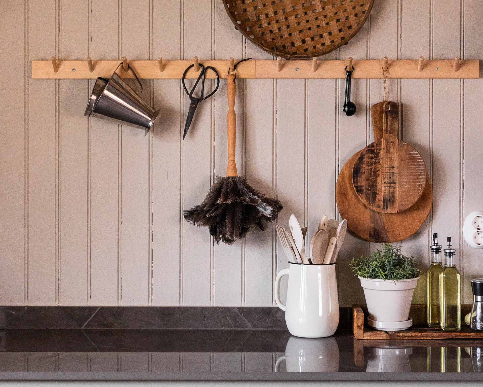 En köksbänk med gröna lådor och en vit pärlspont träpanel, samt dekorationer