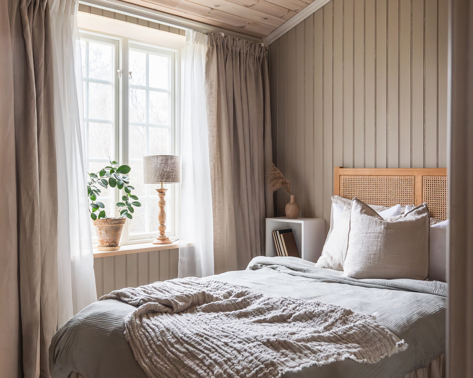 Sovrum, fönster och en träpanel i beige pärlspont