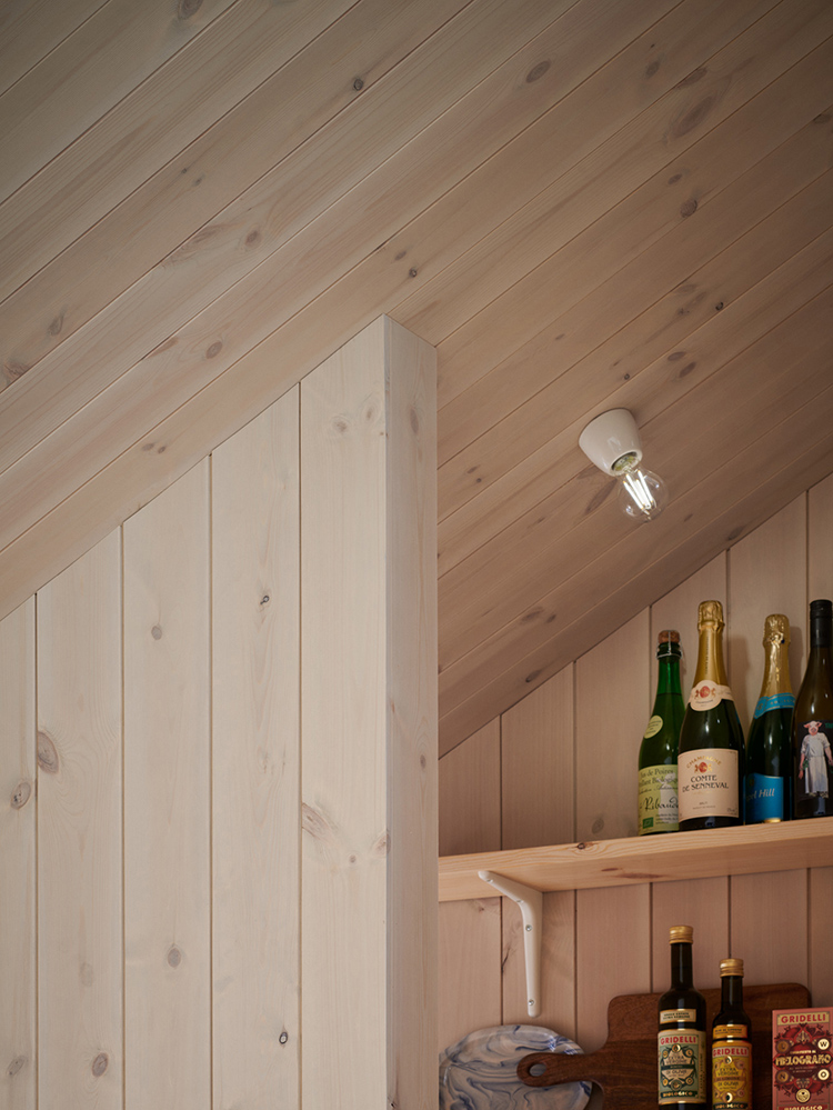 Träpanelen Stilla Morgondis sitter på väggarna och i tak. Längst bort ett öppet skafferi.