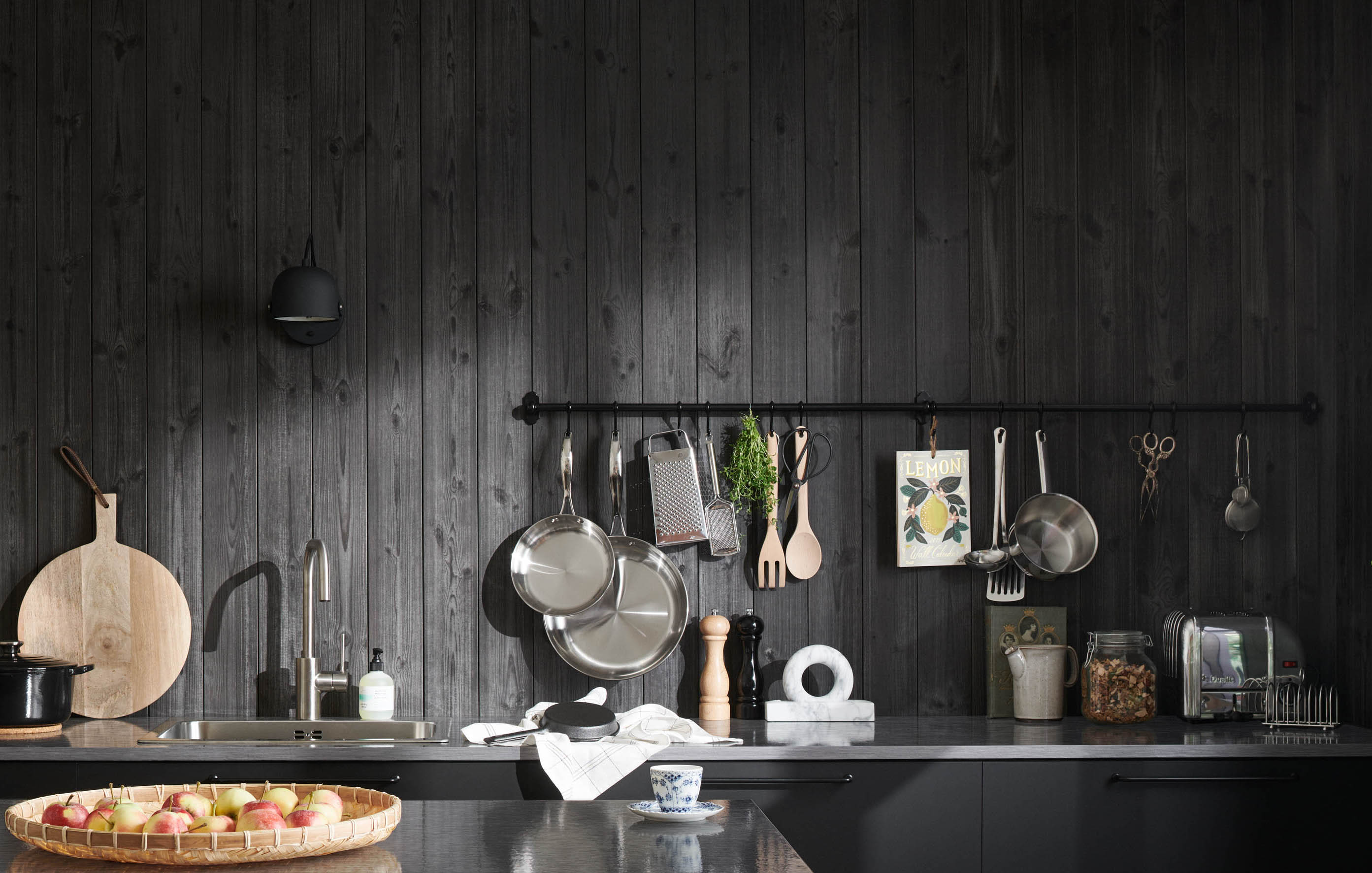 Kök med svart träpanelen sjöbod lava, köksredskap och en grön växt