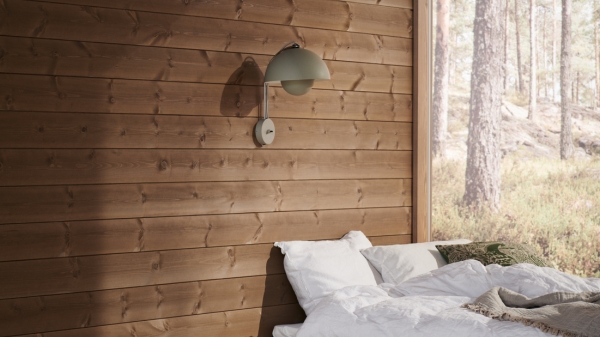 Vitbäddad säng i ett sovrum med bruna träpanelen Stilla Skogsbrun och utsikt på en tallskog från ett stort fönster