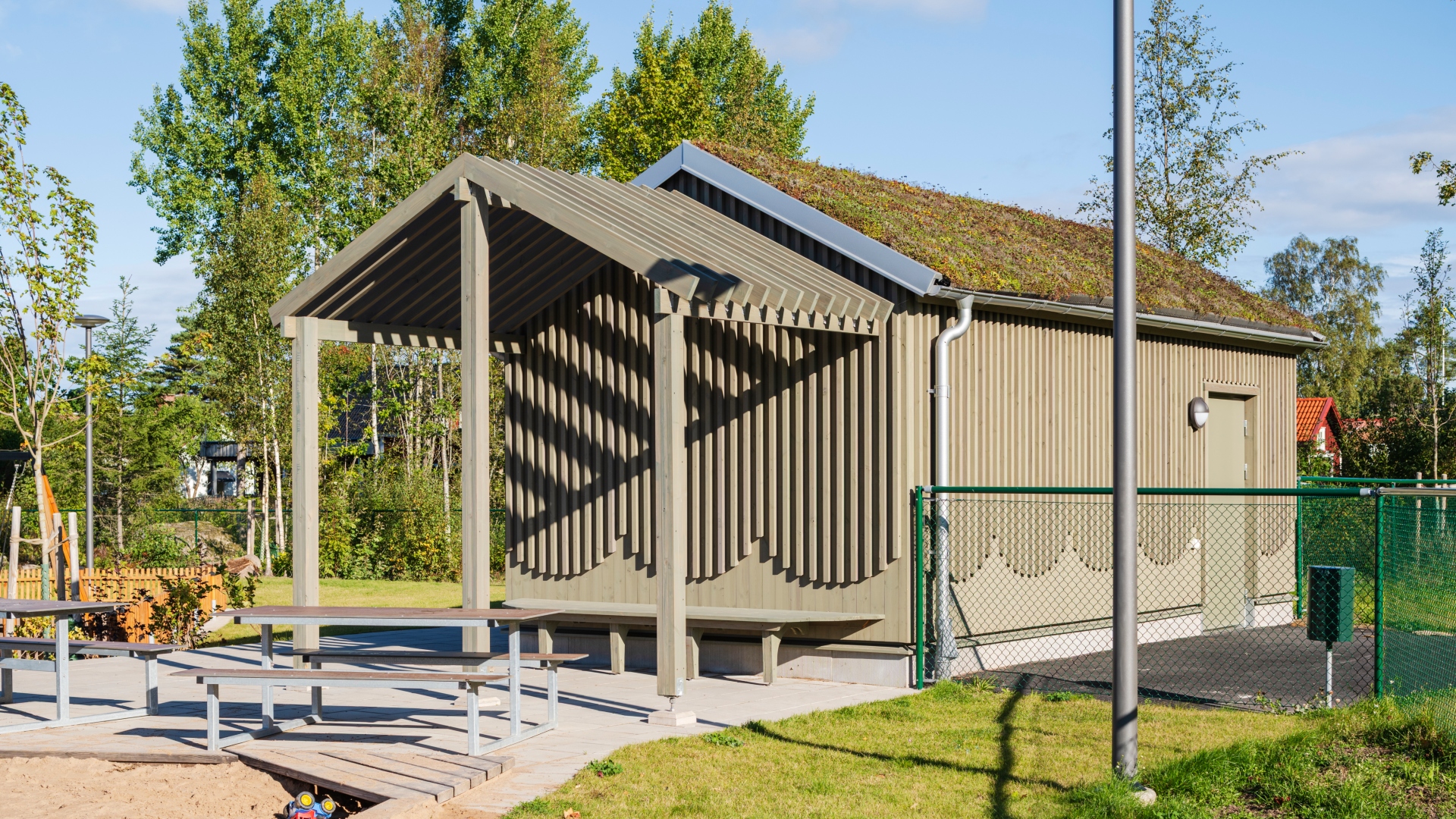 Komplementbyggnad med fasad av pigmenterad ThermoWood i en grön kulör.