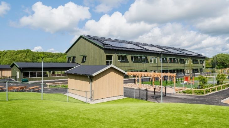 Komplementbyggnad i Kärnfuru KulörOlja Silver framför Limabacka förskola i Kärnfuru KulörOlja Grön