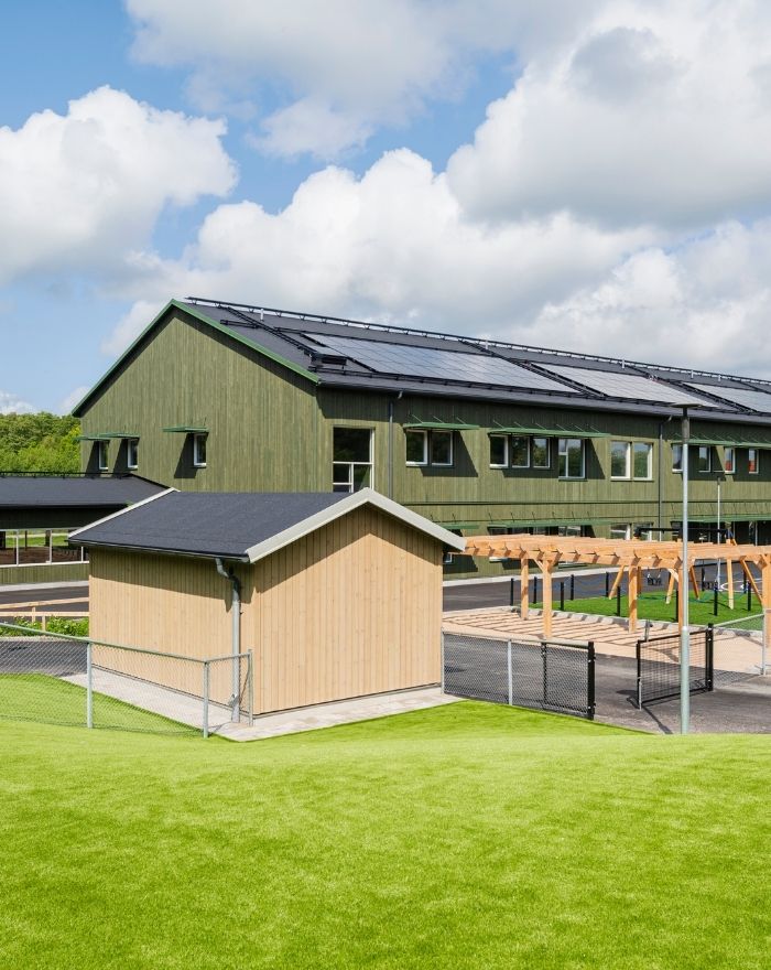 Komplementbyggnad med panel i Kärnfuru KulörOlja Silver framför Limabacka förskola med panel i Kärnfuru KulörOlja Grön.