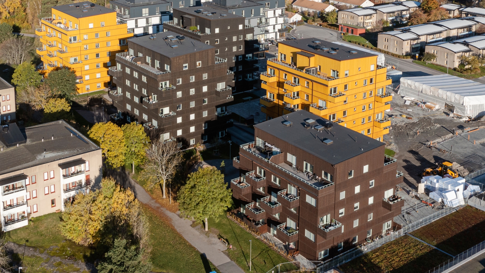 Fem flerbostadshus med fasad av THermoWood BT Pigment Svart, Mahognybrun och Gul.