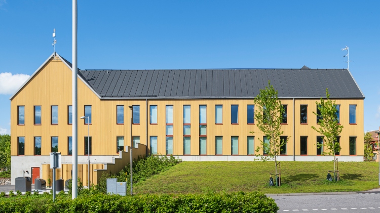 Östra Göinge kommunhus med flaggstång i förgrunden och med fasad av ThermoWood BT Pigment Ockragul