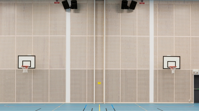 Idrottshall med perforerad Studiopanel på väggarna bakom basketkorgar