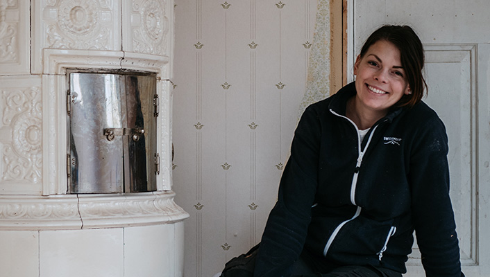 Johanna Berglund framför en kakelugn