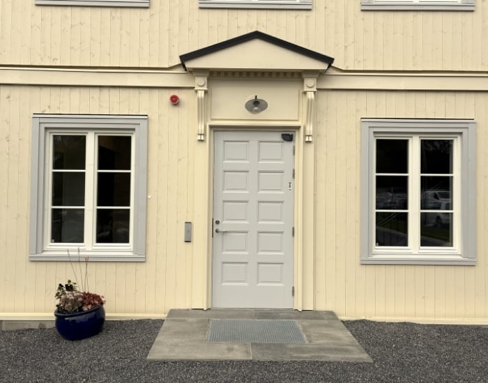 Inngangsparti til Blindern STudenterhjems nye nordfløy med trekledning i gult, lysegrå innramming av vinduene og en lyse grå inngangsdør