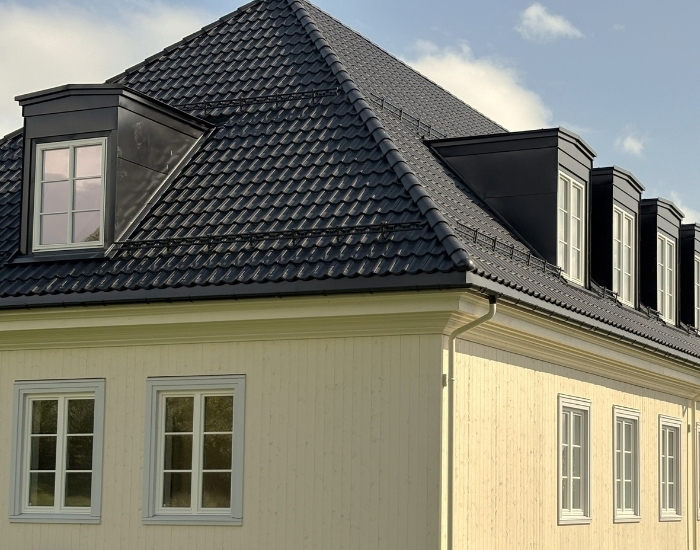 Taket på den nye nordfløyen til Blindern studenterhjem er svart og har karnapper. Kledningen er av tre er lysegul og har ikke synlig innfesting.