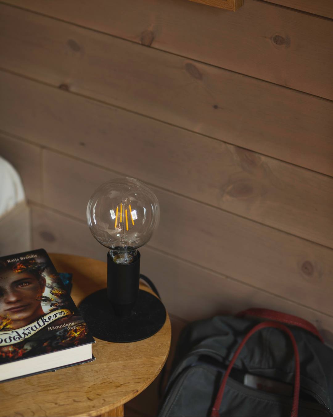 Närbild på en bordslampa utan skärm som står på ett runt träbord
