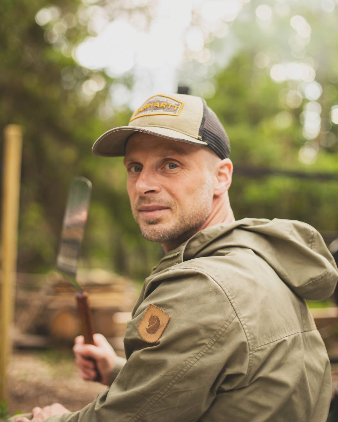En man i gröna friluftskläder ute i naturen tittar mot kameran