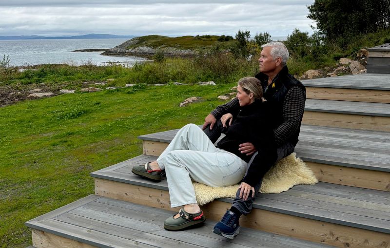 Hege og Jan Roger sitter sammen på terrassen ved Haveng, med havet og naturen på Rolløya i bakgrunnen.