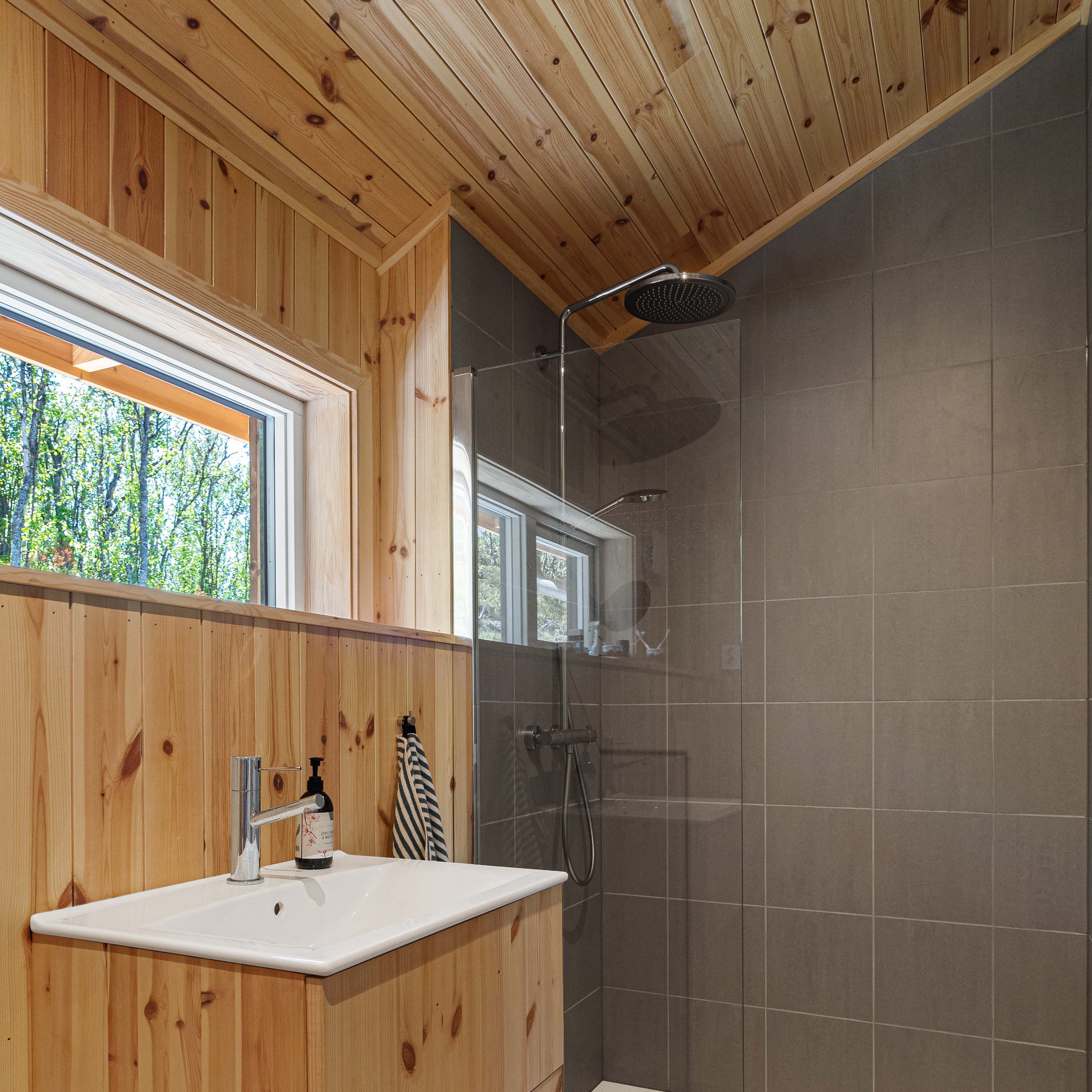 Hyttas to bad har en kombinasjon av furupanel og fliser.