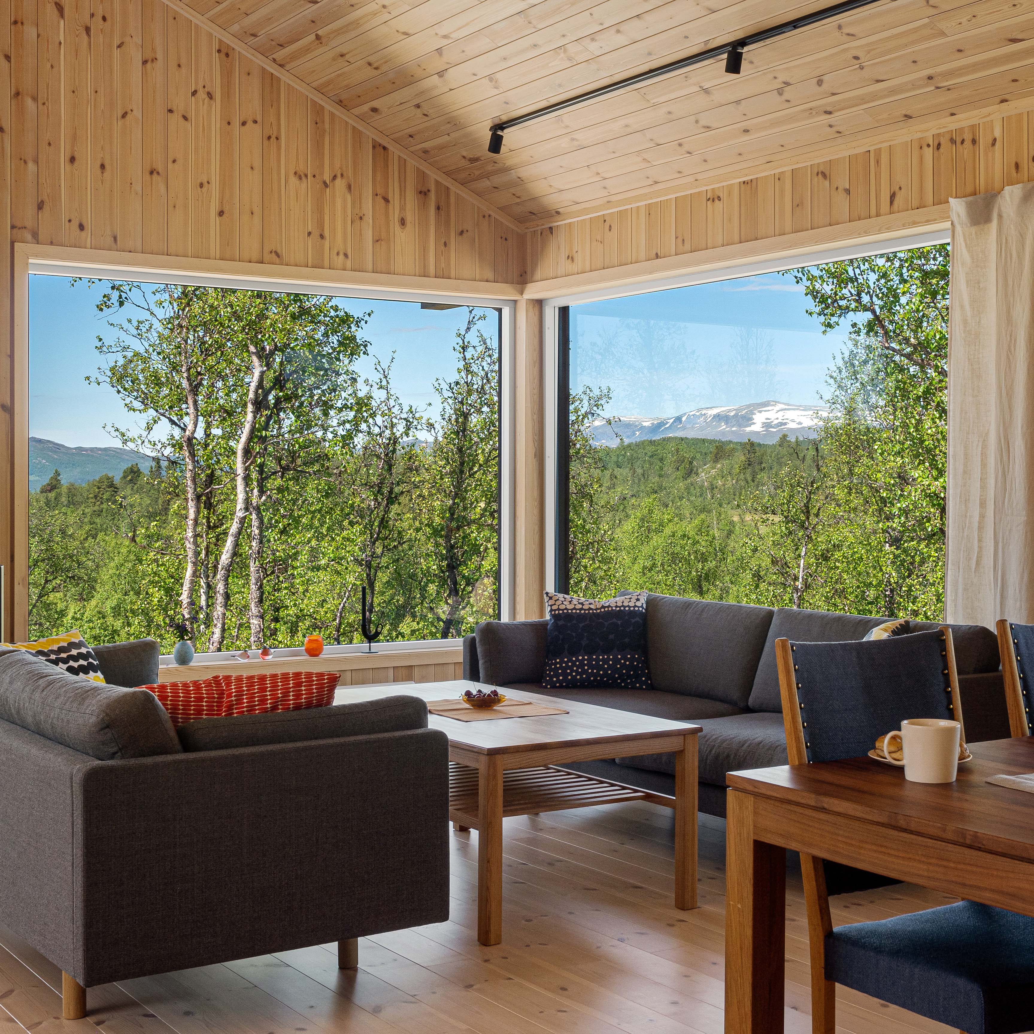 Det lune furugulvet, de store vinduene og furupanelet gir hytta et naturlig og lunt uttrykk.