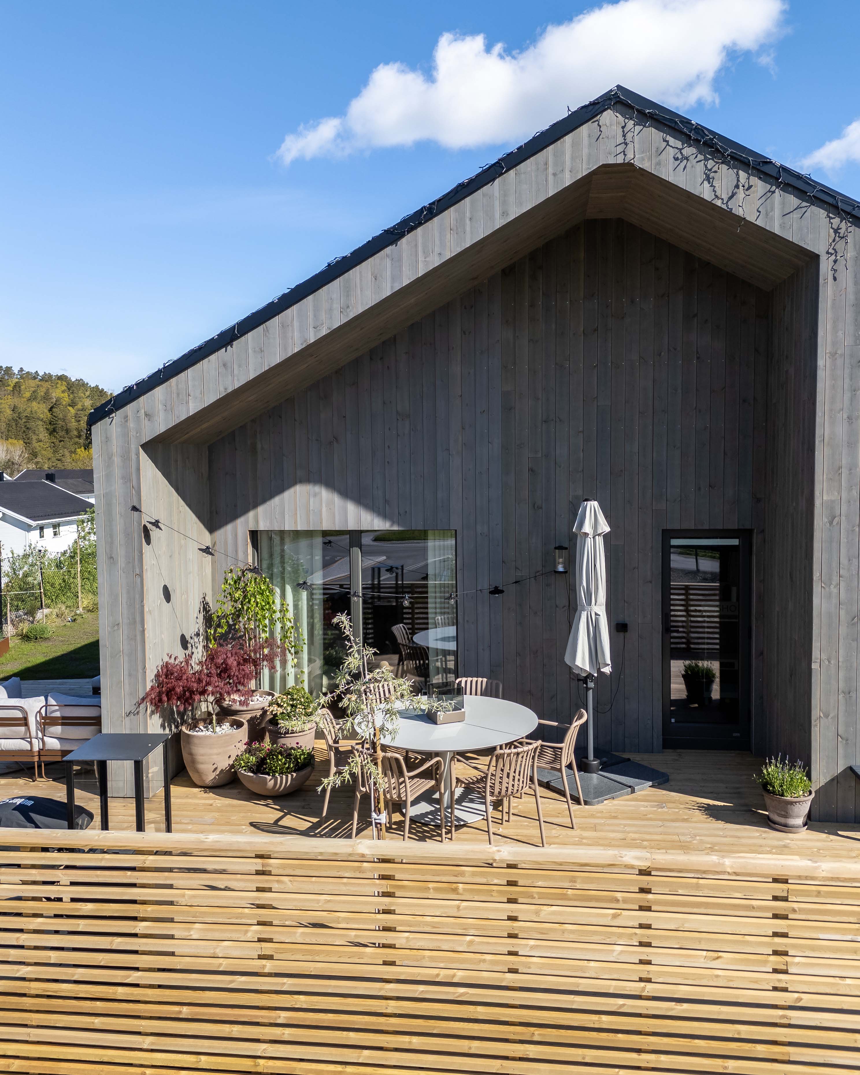 Moderne hus med Moelven Værbitt Gråna kledning og terrasse foran