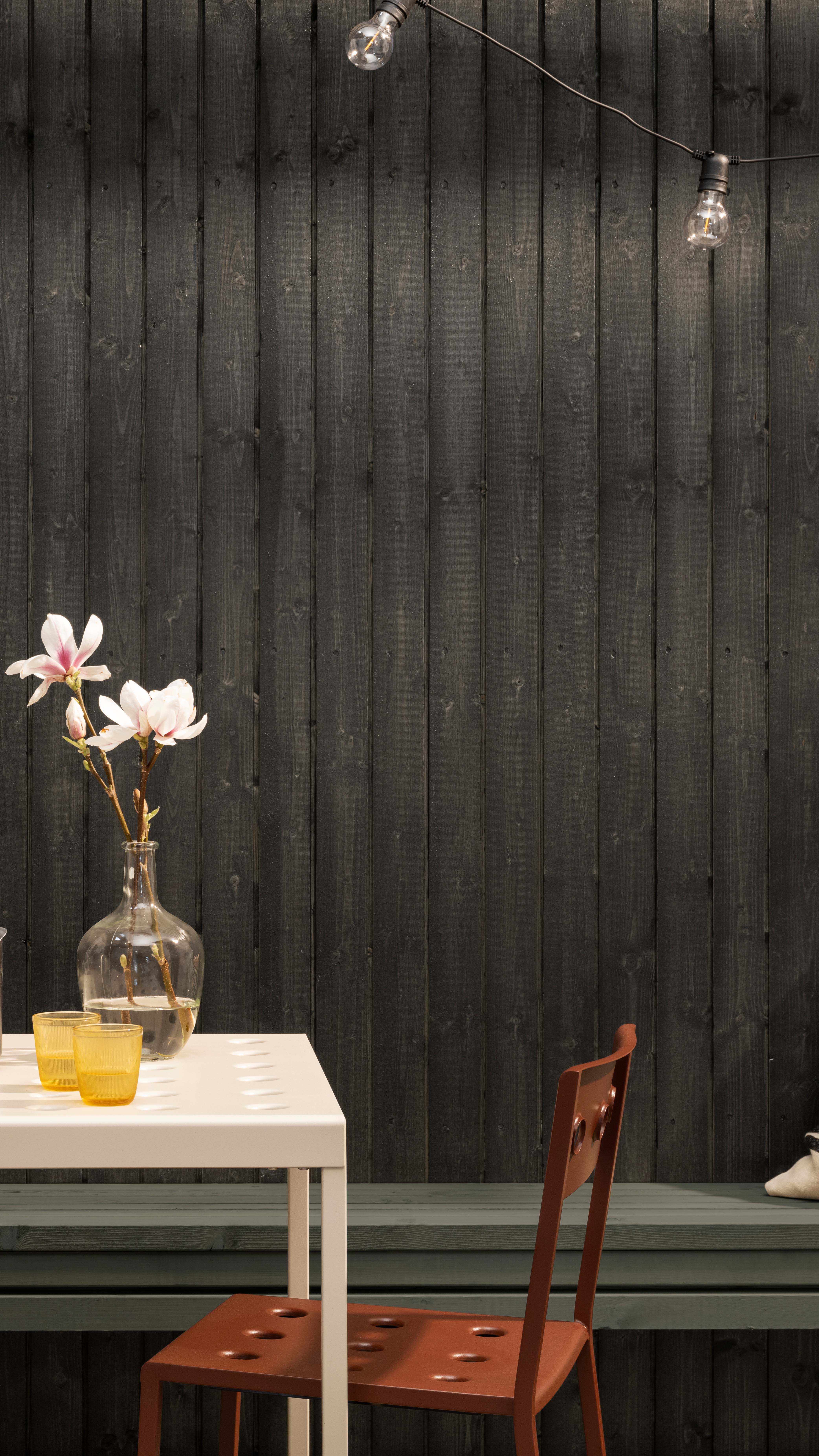 Fasadevegg med bord og stol forann i fargen funkissort