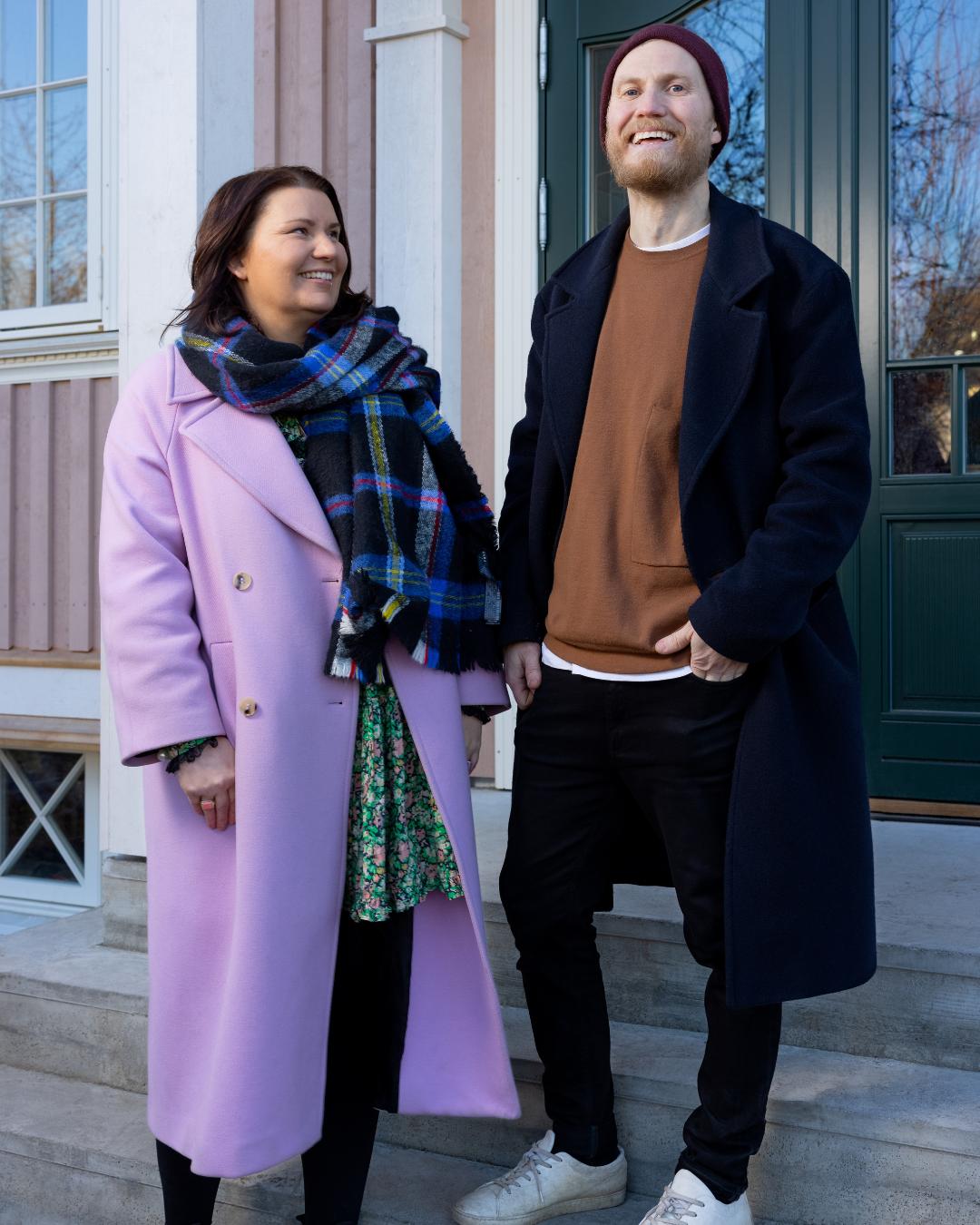 Kine Vinje og Tom Andersen smilende foran inngangen til sitt renoverte hus med rosa Heftig PRO kledning
