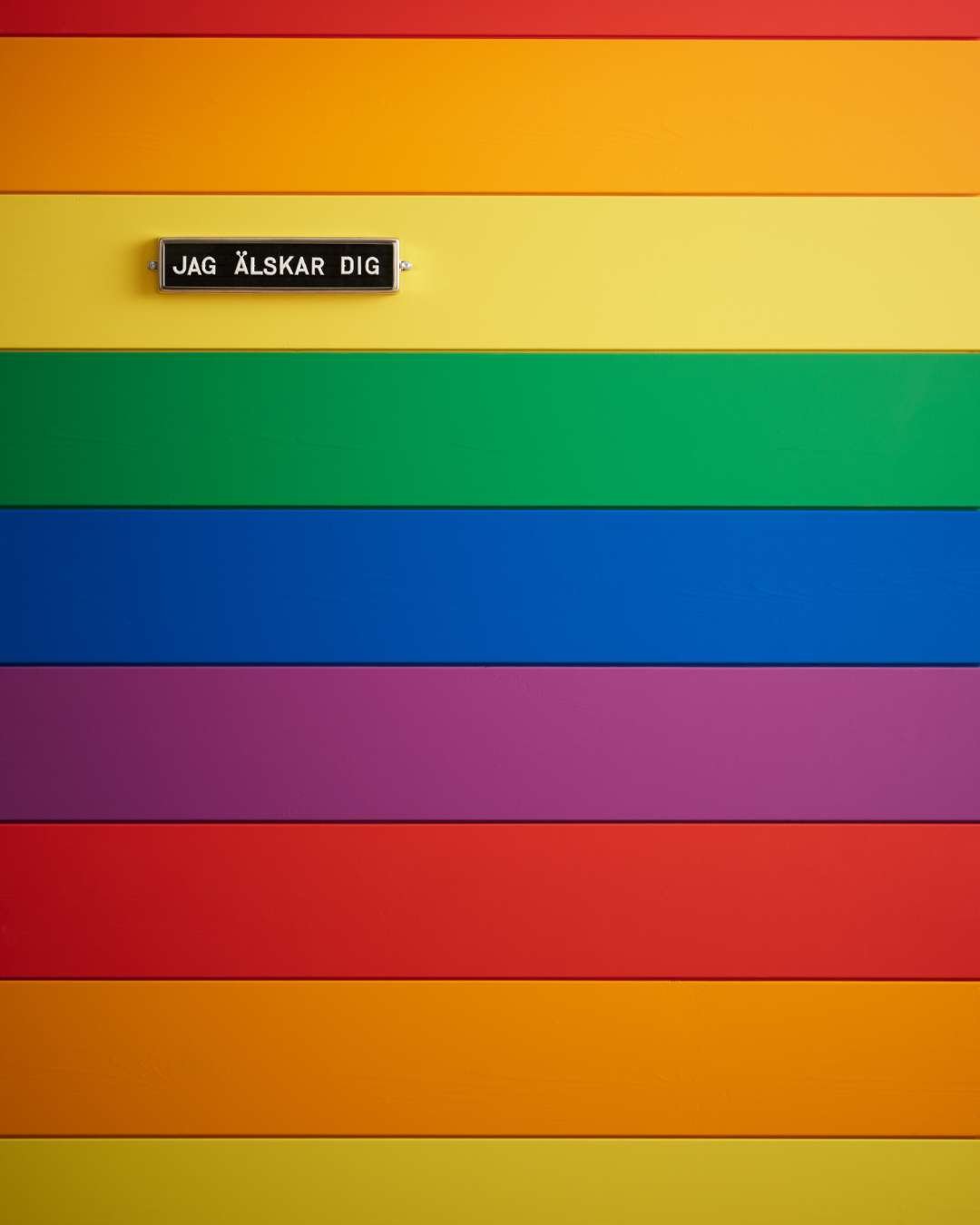 Trepanel sprekk i regnbuefarger med et lite skilt som sier "Jag älskar dig"