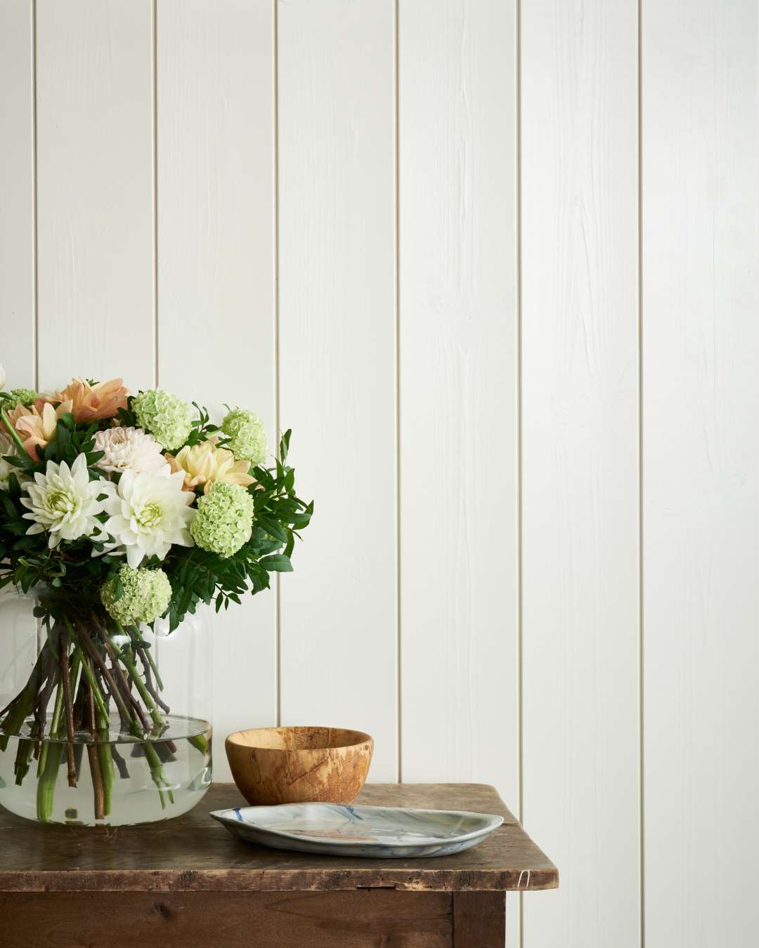 Trepanel sprekk i malt bomull med et lite bord med hvite blomster og et pyntefat