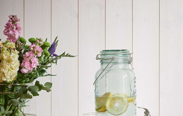 Trepanel Sjøbod Snø med blomster i forgrunnen. En vanndispenser med vann og sitron.